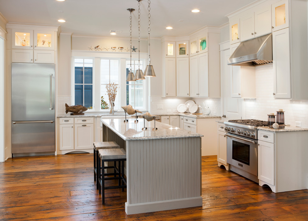 Kitchen - large coastal l-shaped medium tone wood floor kitchen idea in Charleston with a farmhouse sink, recessed-panel cabinets, white cabinets, white backsplash, subway tile backsplash and stainless steel appliances