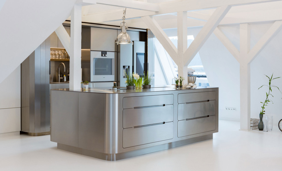 Photo of a large modern galley eat-in kitchen with a drop-in sink, flat-panel cabinets, stainless steel cabinets, stainless steel benchtops, stainless steel appliances, with island, concrete floors and white floor.
