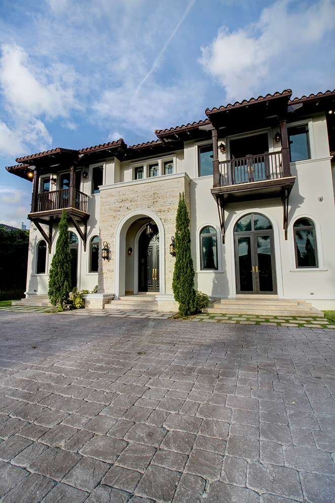 This is an example of a large mediterranean two-storey stucco white house exterior in Miami.