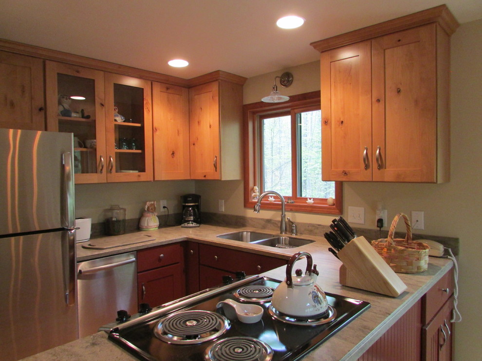 Kitchen - rustic u-shaped light wood floor kitchen idea with an undermount sink, shaker cabinets, red cabinets, solid surface countertops, stainless steel appliances, a peninsula and beige countertops