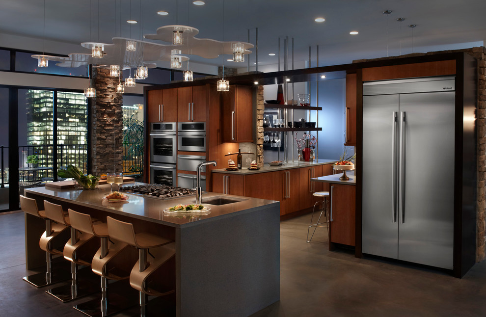 This is an example of a large modern galley open plan kitchen in Boston with an undermount sink, flat-panel cabinets, dark wood cabinets, solid surface benchtops, stainless steel appliances, concrete floors, with island and brown floor.