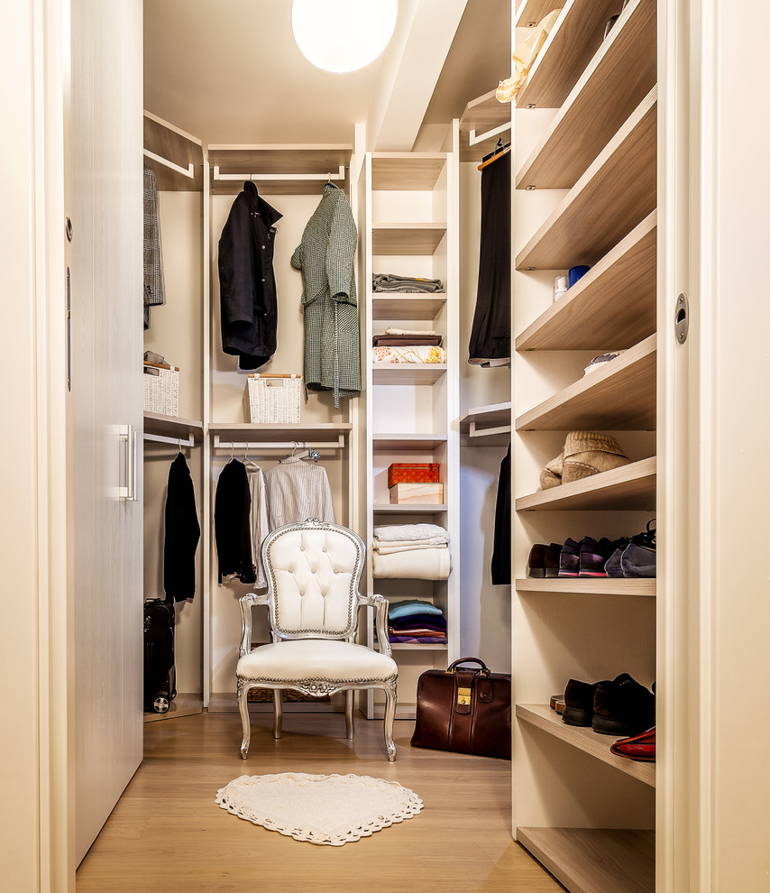 This is an example of a mid-sized contemporary gender-neutral walk-in wardrobe in Rome with open cabinets, beige cabinets, laminate floors and brown floor.