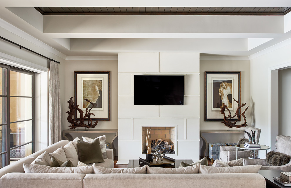 Photo of a mid-sized transitional enclosed family room in Charlotte with beige walls, a wall-mounted tv, a standard fireplace and a plaster fireplace surround.