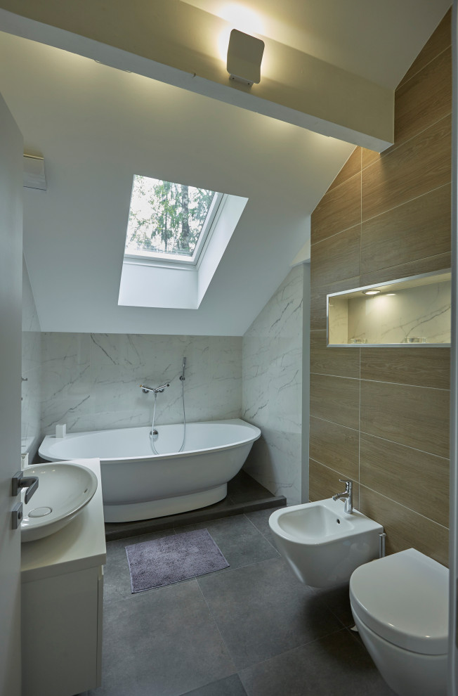 This is an example of a modern bathroom in Other with white cabinets, a freestanding bath, brown tiles, wood-effect tiles, a vessel sink, grey floors, white worktops, a single sink and a vaulted ceiling.