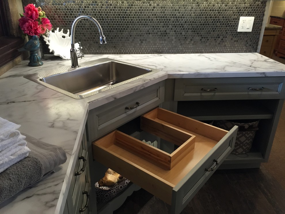 Small transitional l-shaped vinyl floor home design photo with a single-bowl sink, recessed-panel cabinets, gray cabinets, laminate countertops and gray walls