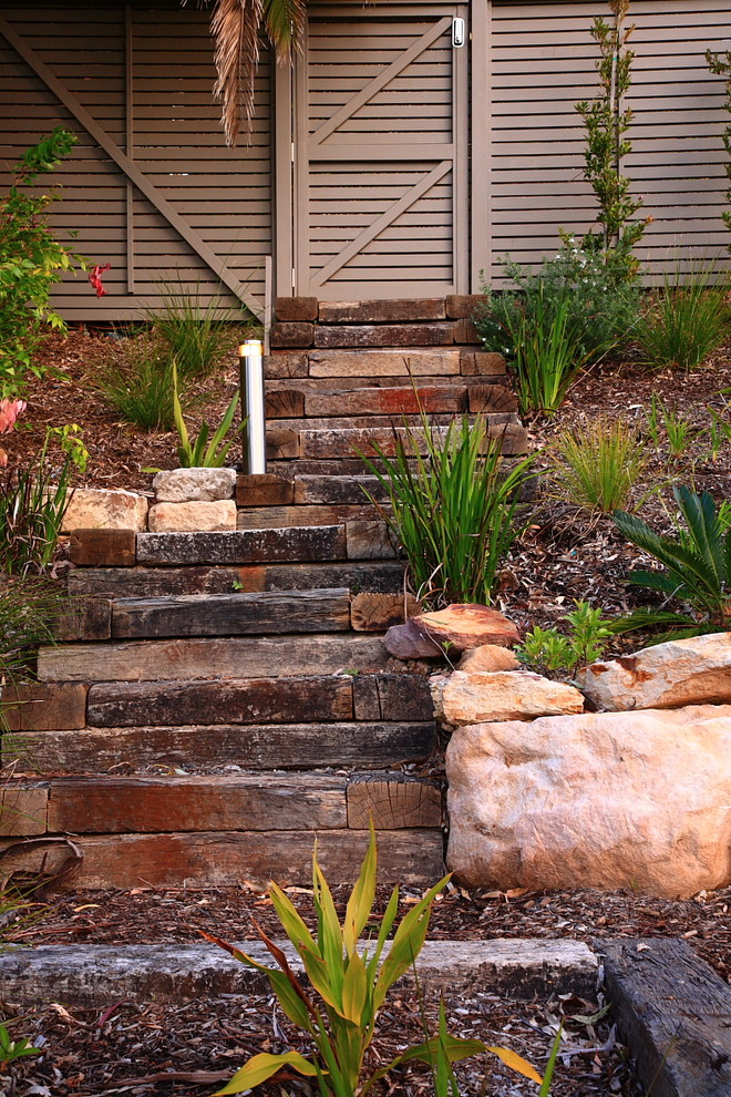 Design ideas for a mid-sized tropical sloped partial sun garden in Sydney with a garden path.