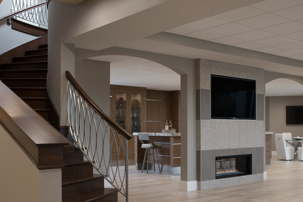 Inspiration for an expansive contemporary walk-out basement in Detroit with beige walls, porcelain floors, a standard fireplace and a tile fireplace surround.