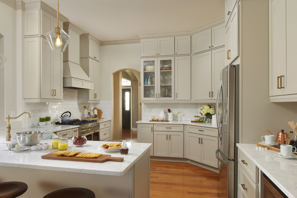 Mid-sized transitional u-shaped medium tone wood floor and brown floor kitchen photo in Atlanta with a farmhouse sink, shaker cabinets, gray cabinets, quartz countertops, white backsplash, subway tile backsplash, stainless steel appliances, a peninsula and white countertops