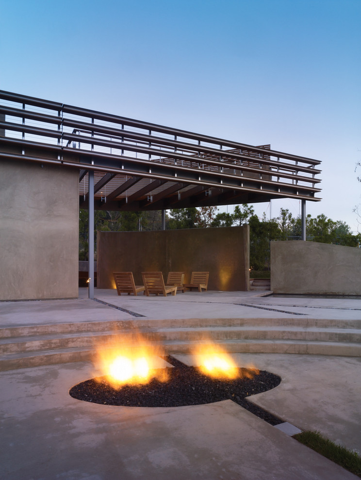 Photo of a mid-sized modern backyard patio in Los Angeles with a fire feature, concrete slab and a pergola.