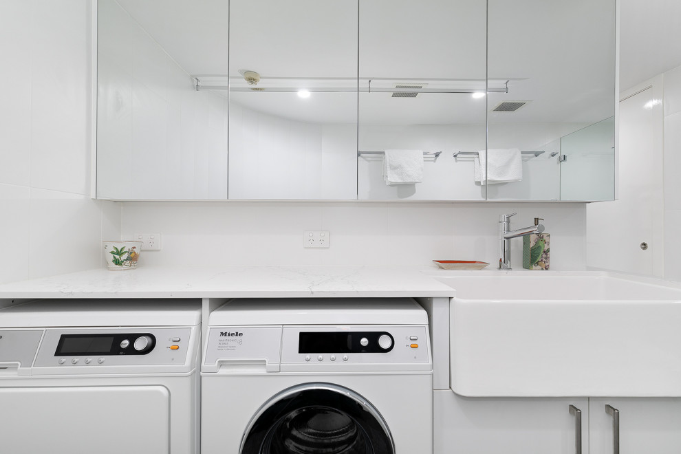 Design ideas for a small contemporary utility room in Brisbane with a farmhouse sink, white splashback, ceramic splashback, white walls, porcelain floors, a side-by-side washer and dryer, grey floor and white benchtop.