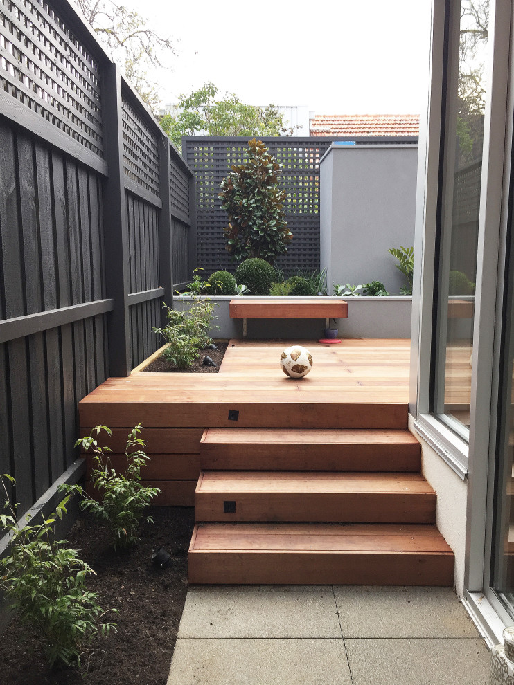 Small modern courtyard partial sun formal garden in Melbourne with a container garden and decking for summer.