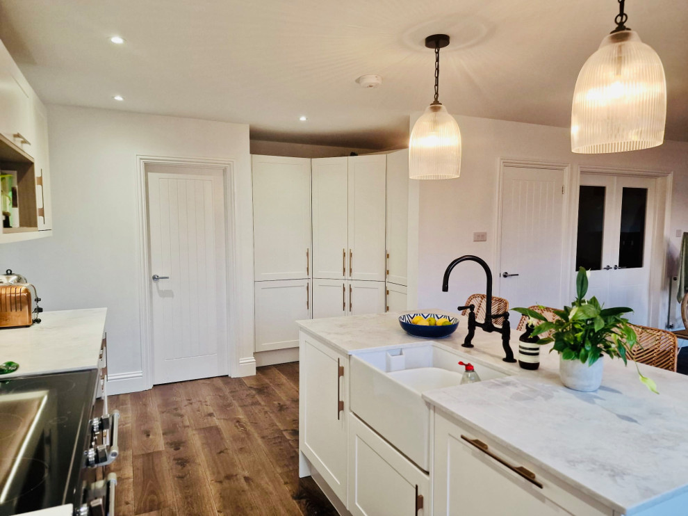 Mid-sized contemporary eat-in kitchen in Other with a farmhouse sink, shaker cabinets, white cabinets, quartz benchtops, medium hardwood floors, with island and grey benchtop.