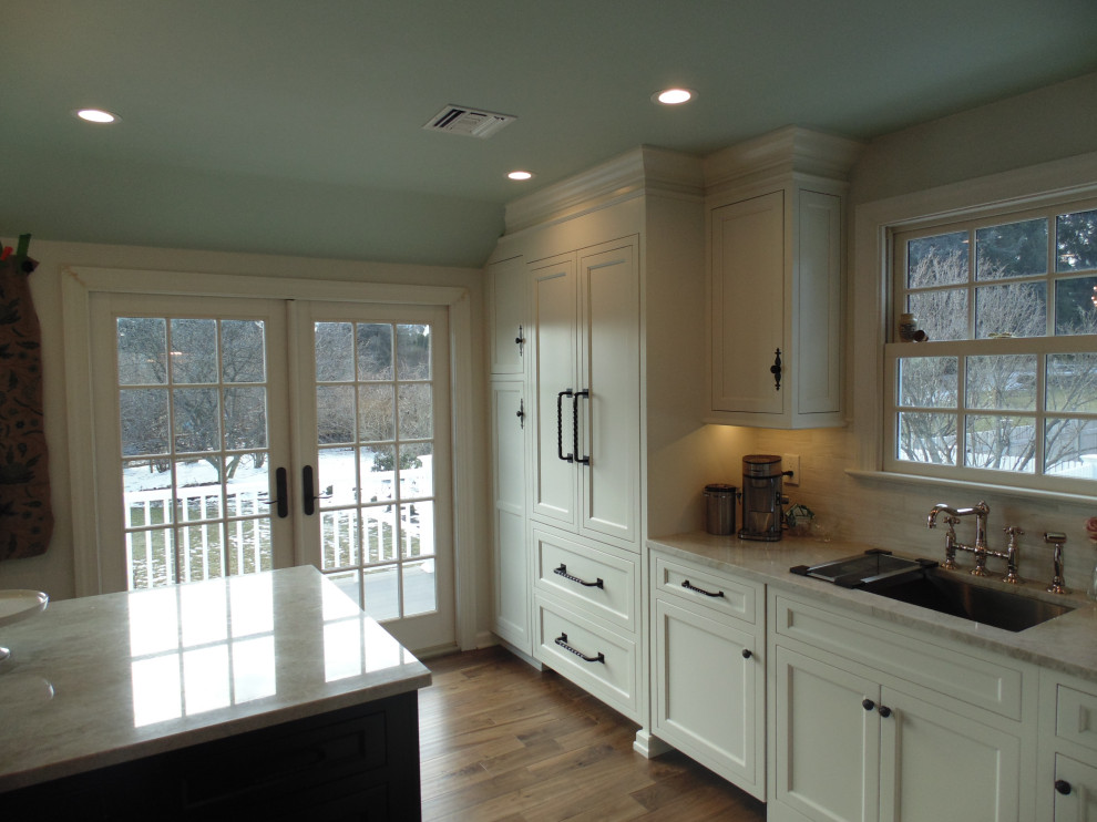 Eat-in kitchen - large transitional u-shaped medium tone wood floor and brown floor eat-in kitchen idea with an undermount sink, recessed-panel cabinets, white cabinets, quartzite countertops, beige backsplash, subway tile backsplash, stainless steel appliances, an island and beige countertops