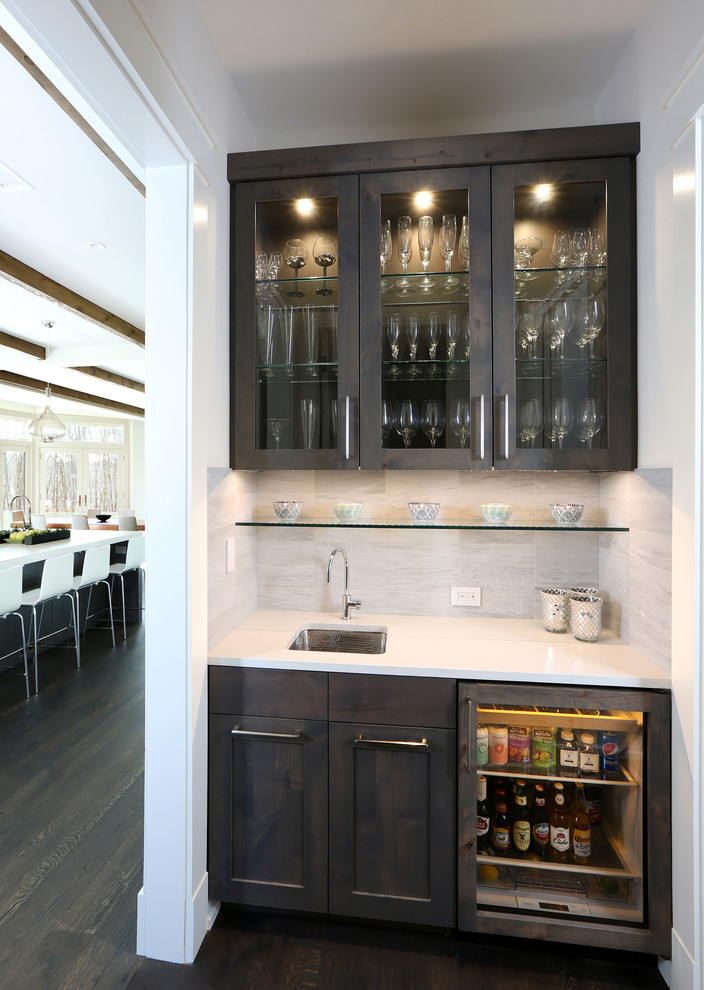 Inspiration for an expansive contemporary wet bar in New York with recessed-panel cabinets, dark wood cabinets, quartz benchtops, white splashback and dark hardwood floors.