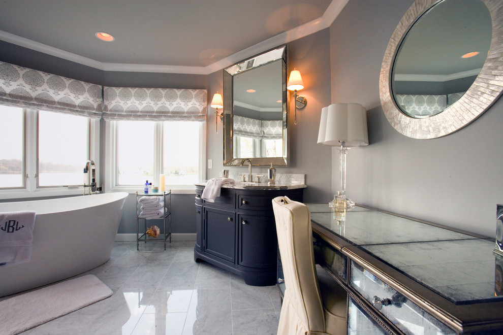 Photo of a large traditional master wet room bathroom in Detroit with beaded inset cabinets, black cabinets, a freestanding tub, a wall-mount toilet, white tile, marble, grey walls, marble floors, an undermount sink, marble benchtops, white floor, a hinged shower door and white benchtops.