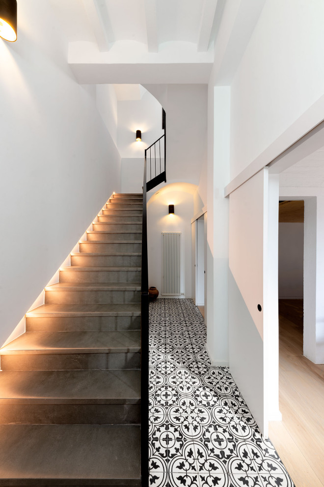 Mittelgroße Nordische Treppe in U-Form mit gefliesten Treppenstufen, gefliesten Setzstufen und Stahlgeländer in Barcelona