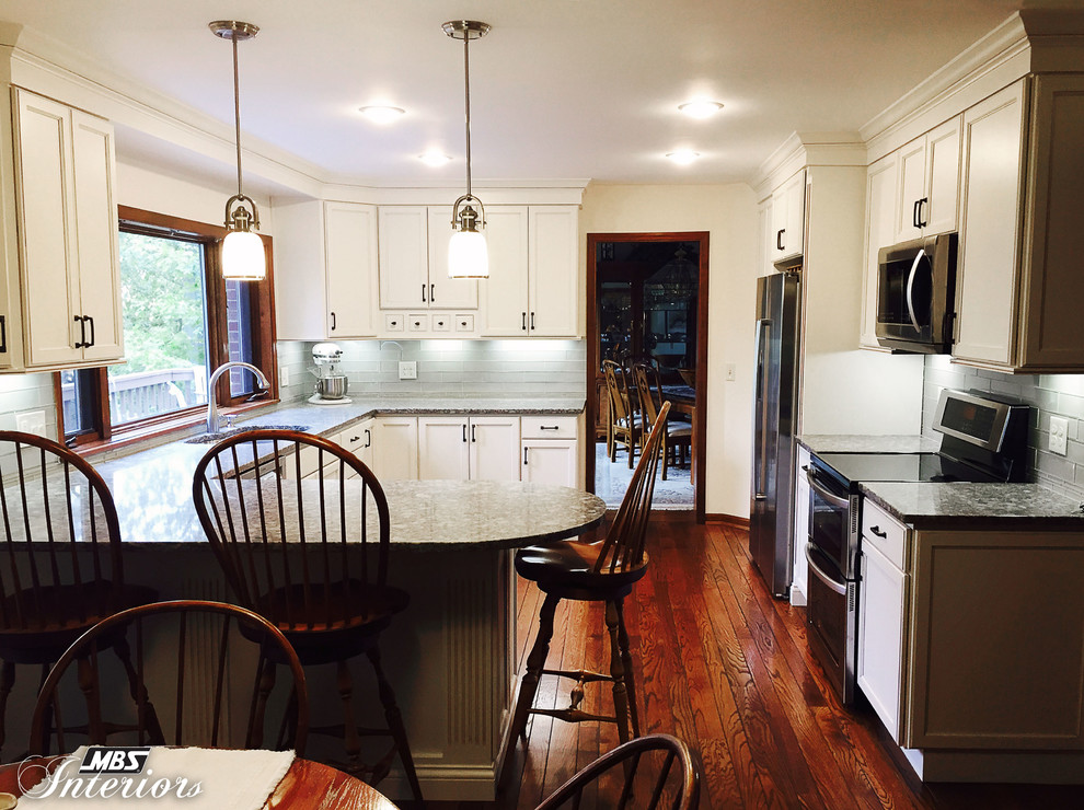 Inspiration for a transitional u-shaped enclosed kitchen remodel with an undermount sink, flat-panel cabinets, white cabinets, quartz countertops, gray backsplash, subway tile backsplash, stainless steel appliances and a peninsula