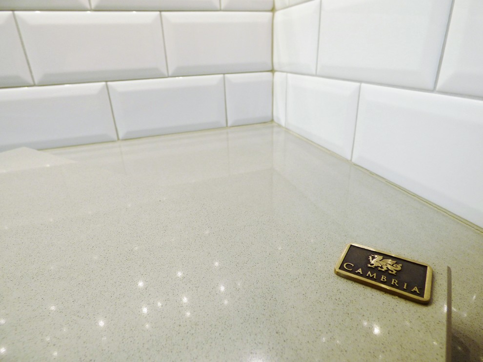 Inspiration for a transitional l-shaped porcelain tile eat-in kitchen remodel with an undermount sink, recessed-panel cabinets, medium tone wood cabinets, quartz countertops, white backsplash, subway tile backsplash, stainless steel appliances and an island