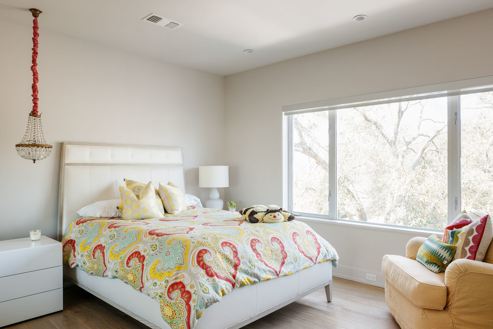 Photo of a contemporary bedroom in Houston with white walls and light hardwood floors.