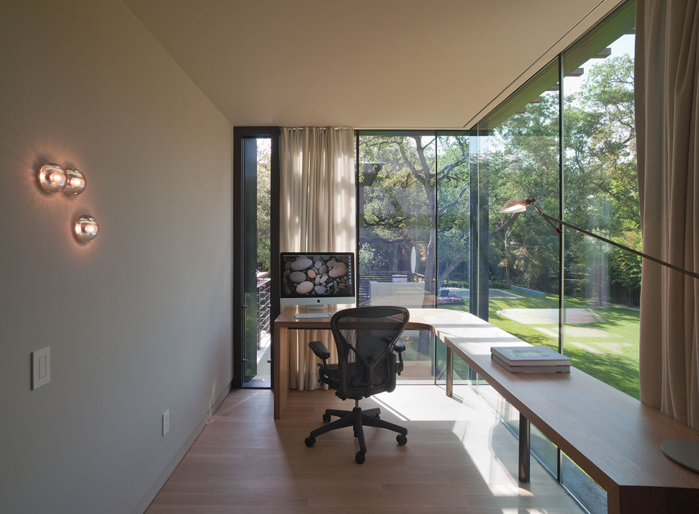 This is an example of a mid-sized modern home studio in Austin with grey walls, medium hardwood floors, a freestanding desk, no fireplace and brown floor.