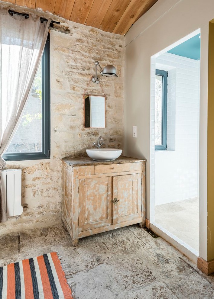 Photo of a mediterranean bathroom in Other with light wood cabinets, beige tile, stone tile, white walls, a vessel sink, wood benchtops, grey floor, brown benchtops and recessed-panel cabinets.