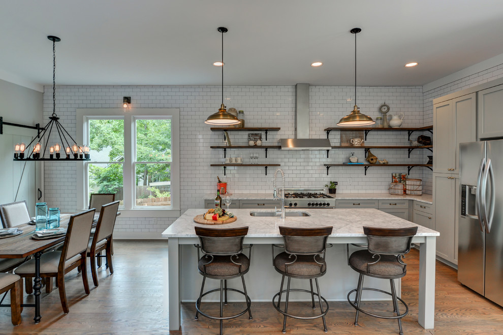 Country l-shaped eat-in kitchen in Atlanta with an undermount sink, shaker cabinets, grey cabinets, white splashback, subway tile splashback, stainless steel appliances, dark hardwood floors, with island and brown floor.