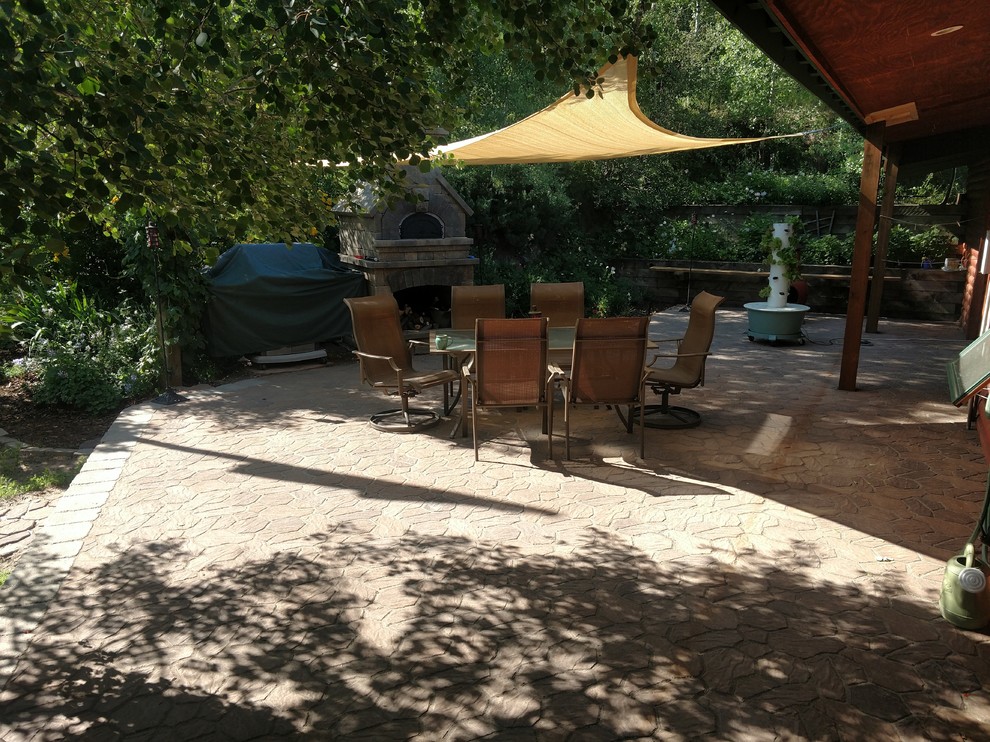 This is an example of a mid-sized country backyard patio in Other with an outdoor kitchen, an awning and natural stone pavers.