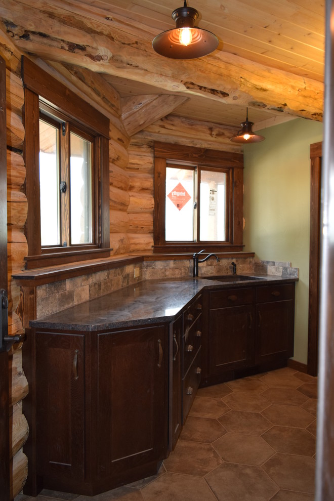 Inspiration for a rustic u-shaped dark wood floor eat-in kitchen remodel with a farmhouse sink, raised-panel cabinets, dark wood cabinets, granite countertops, beige backsplash, stone tile backsplash, stainless steel appliances and an island