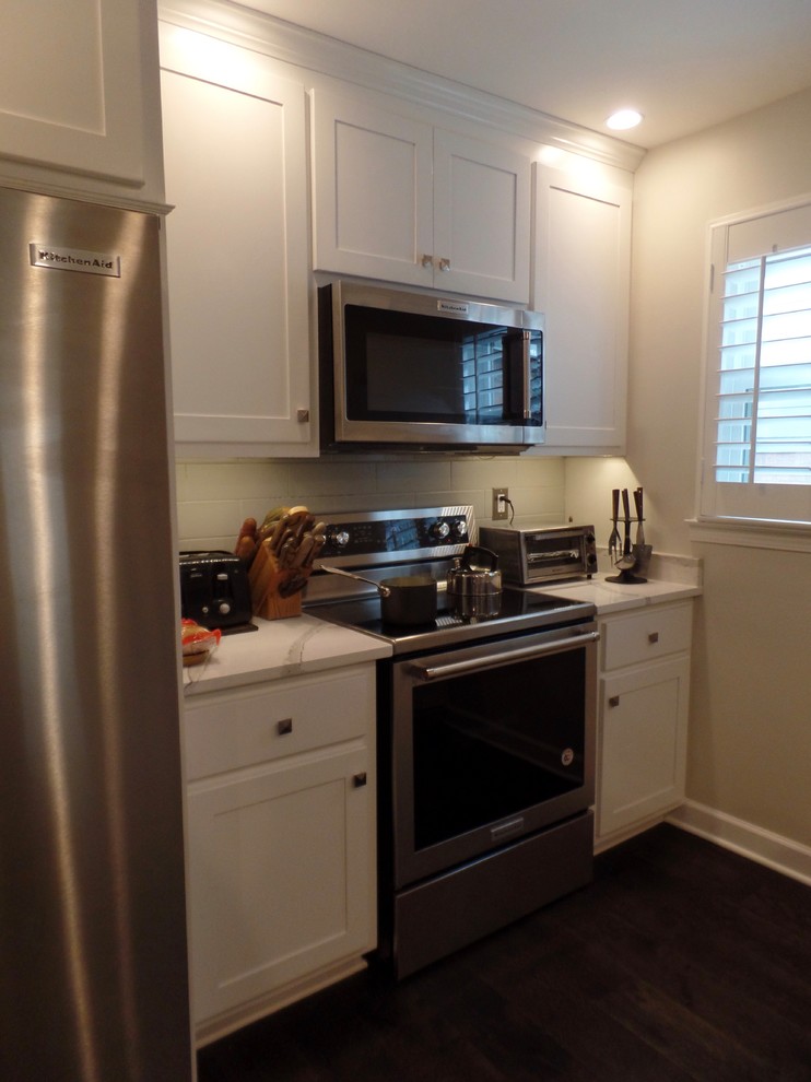Small transitional galley dark wood floor and brown floor open concept kitchen photo with a farmhouse sink, shaker cabinets, white cabinets, quartz countertops, gray backsplash, cement tile backsplash, stainless steel appliances and no island