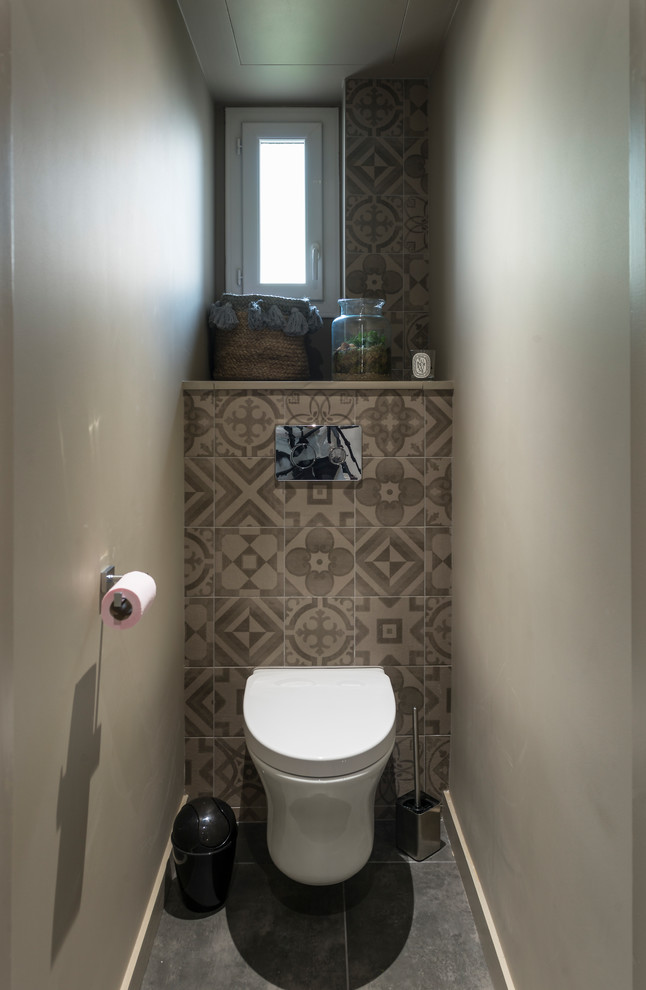 This is an example of a mid-sized contemporary powder room in Grenoble with a wall-mount toilet, brown tile, cement tile, brown walls, ceramic floors, laminate benchtops and grey floor.