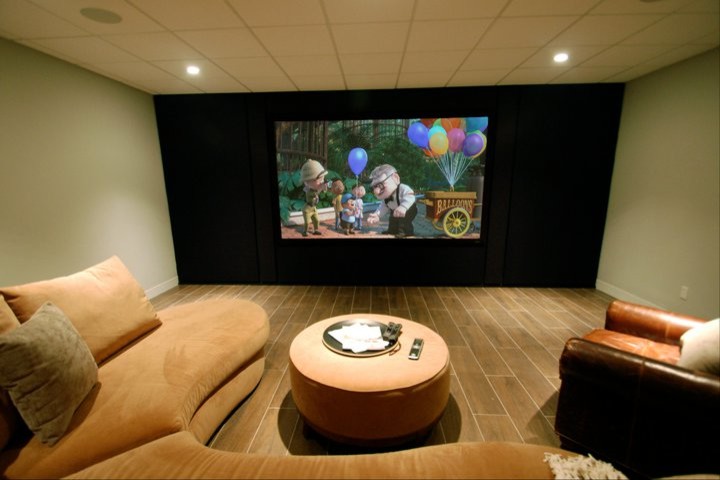 Mid-sized transitional enclosed home theatre in New York with green walls, porcelain floors, a built-in media wall and brown floor.