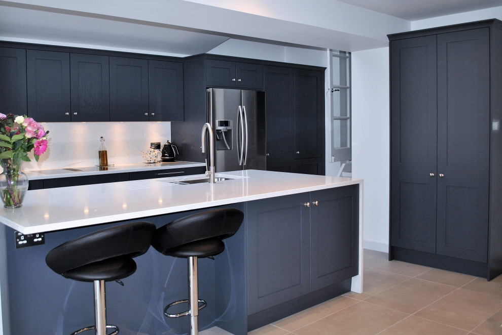 Design ideas for a large modern single-wall eat-in kitchen in London with an integrated sink, shaker cabinets, blue cabinets, quartzite benchtops, white splashback, stone slab splashback, stainless steel appliances, porcelain floors, with island, grey floor and white benchtop.