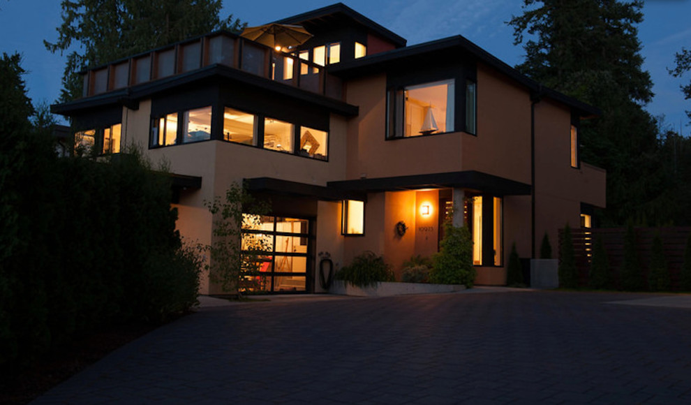 Photo of a large modern three-storey stucco beige house exterior in Vancouver with a flat roof.