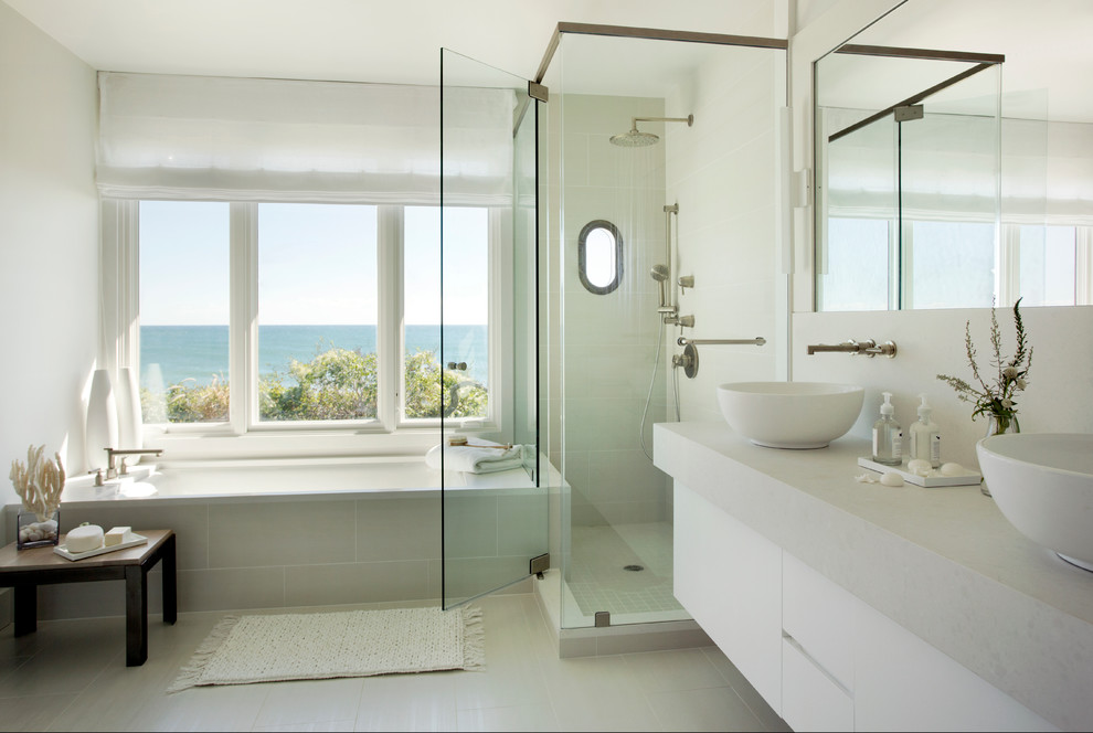 Design ideas for a large beach style master bathroom in Boston with a vessel sink, flat-panel cabinets, white cabinets, an undermount tub, a corner shower, beige tile, beige walls, porcelain floors, engineered quartz benchtops, grey floor, a hinged shower door and grey benchtops.