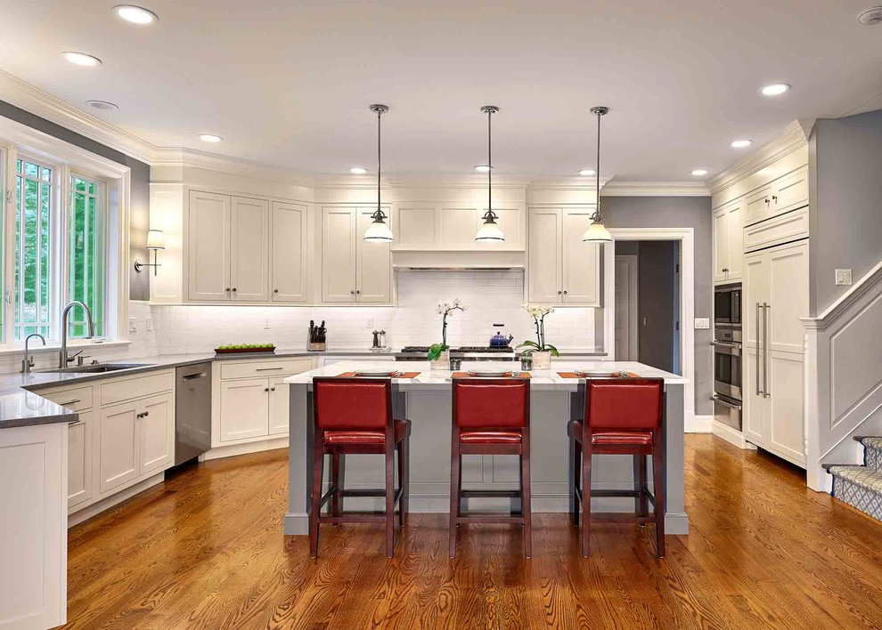 Inspiration for a large transitional l-shaped medium tone wood floor and brown floor eat-in kitchen remodel in Bridgeport with a drop-in sink, beaded inset cabinets, white cabinets, limestone countertops, white backsplash, ceramic backsplash, stainless steel appliances, an island and gray countertops