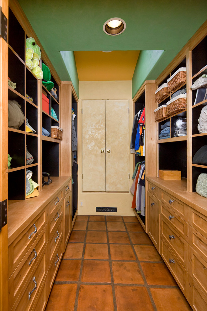 Photo of an eclectic gender-neutral storage and wardrobe in Santa Barbara with shaker cabinets, light wood cabinets and terra-cotta floors.