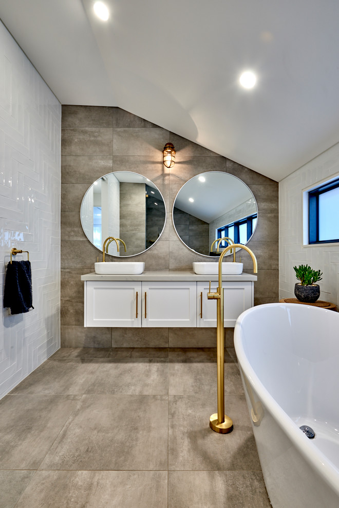 Inspiration for a large contemporary master wet room bathroom in Sydney with shaker cabinets, white cabinets, engineered quartz benchtops, a freestanding tub, a vessel sink, brown floor, a wall-mount toilet, white tile, subway tile, white walls, ceramic floors, an open shower and white benchtops.