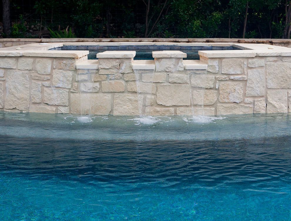 Mid-sized traditional backyard custom-shaped natural pool in Austin with decking and a hot tub.