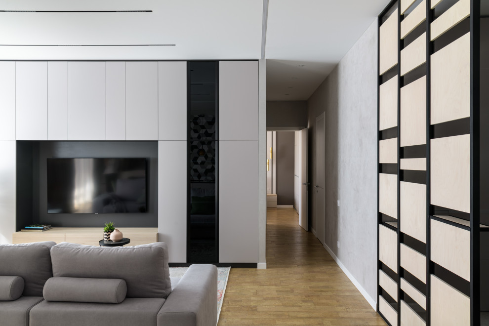 На фото: открытая, объединенная, серо-белая гостиная комната среднего размера:: освещение в современном стиле с с книжными шкафами и полками, серыми стенами, пробковым полом и телевизором на стене с