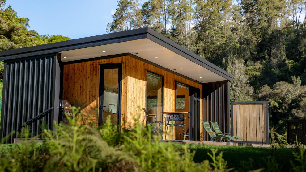 Idées déco pour une façade de Tiny House marron craftsman en bois de plain-pied avec un toit plat et un toit gris.
