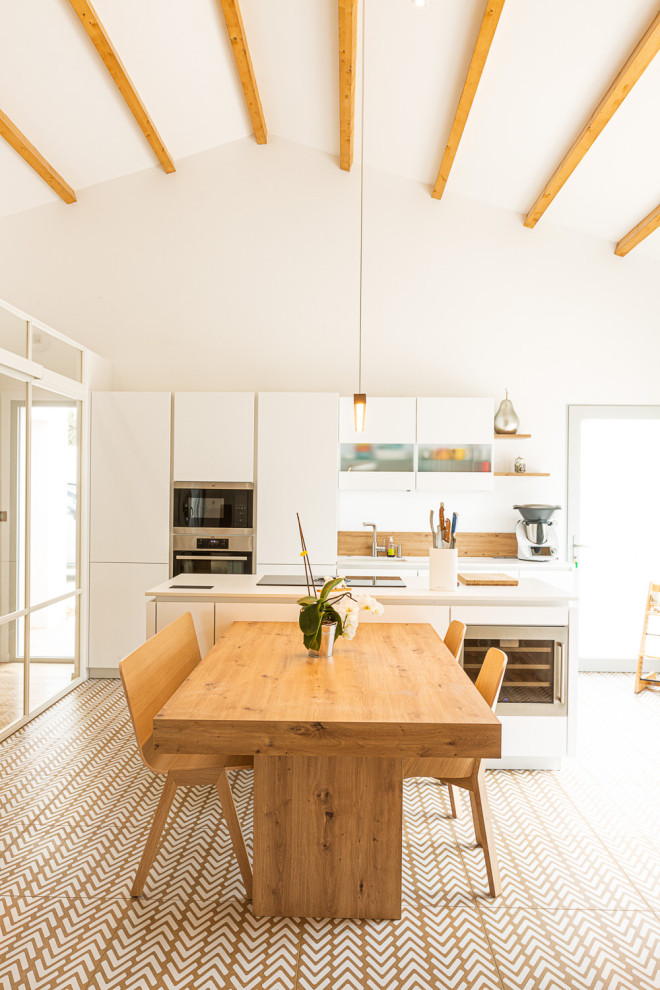 Foto på ett stort funkis vit kök, med en enkel diskho, brunt stänkskydd, rostfria vitvaror, en köksö och brunt golv