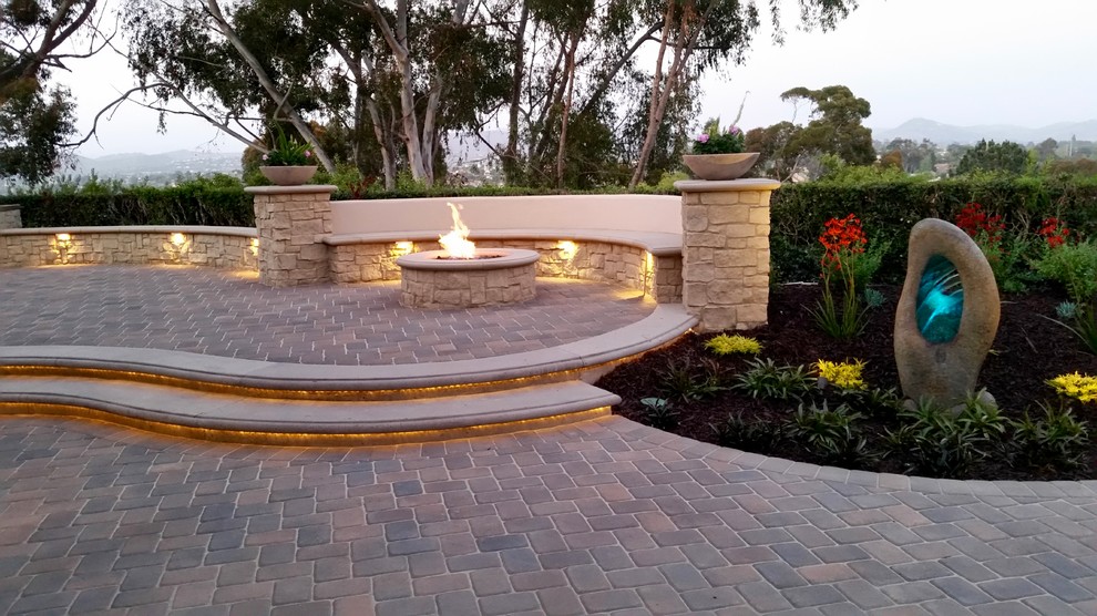 This is an example of a mid-sized contemporary backyard garden in San Diego with a fire feature and natural stone pavers.