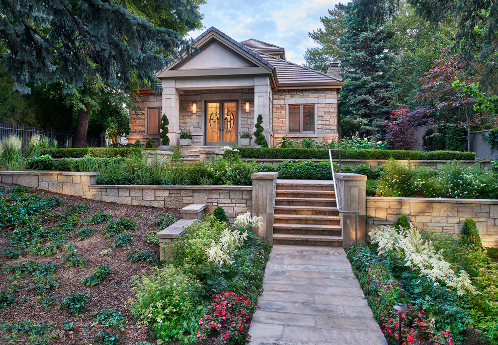 This is an example of a large transitional front yard full sun formal garden in Denver with a retaining wall and natural stone pavers.