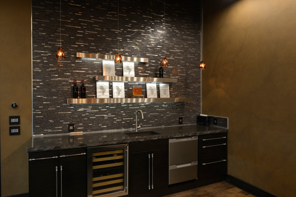 This is an example of a mid-sized contemporary single-wall wet bar in Seattle with an undermount sink, flat-panel cabinets, black cabinets, solid surface benchtops, grey splashback, matchstick tile splashback, porcelain floors and brown floor.