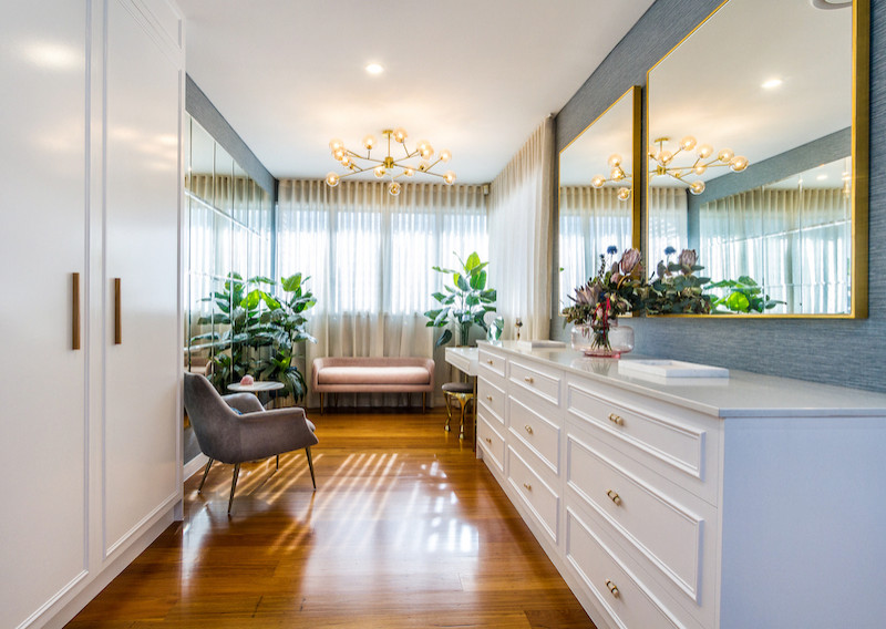 This is an example of a large contemporary gender-neutral walk-in wardrobe in Brisbane with raised-panel cabinets, white cabinets, medium hardwood floors and brown floor.
