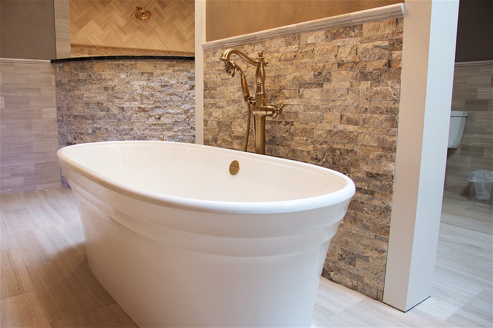 This is an example of a large contemporary master bathroom in Austin with beaded inset cabinets, dark wood cabinets, a freestanding tub, an open shower, a bidet, beige tile, beige walls, a drop-in sink, granite benchtops, porcelain floors and beige floor.