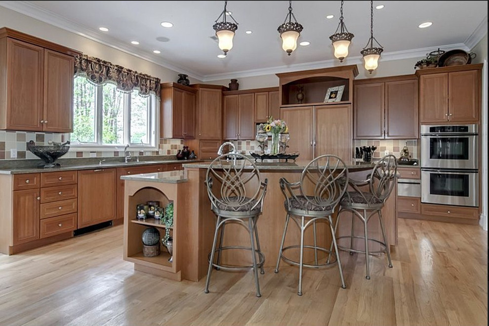 Inspiration for a huge transitional l-shaped limestone floor and beige floor enclosed kitchen remodel in DC Metro with a double-bowl sink, recessed-panel cabinets, medium tone wood cabinets, granite countertops, multicolored backsplash, stainless steel appliances, a peninsula and ceramic backsplash