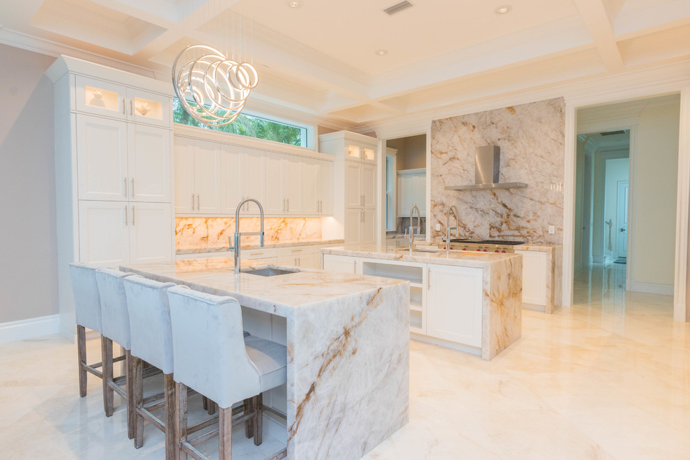 Huge transitional u-shaped marble floor and white floor open concept kitchen photo with an undermount sink, flat-panel cabinets, white cabinets, quartzite countertops, white backsplash, stone slab backsplash and two islands