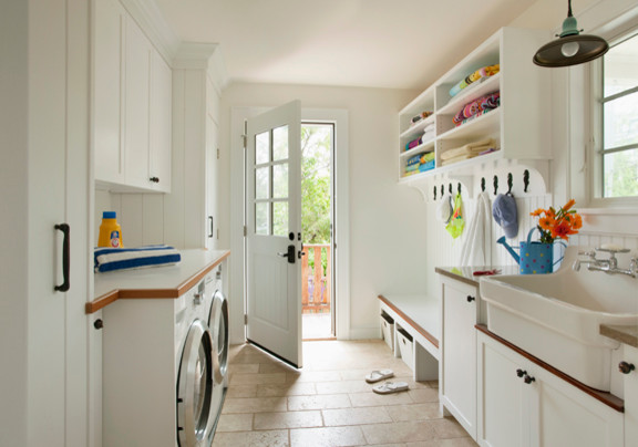 Mid-sized traditional galley utility room in Boston with a farmhouse sink, recessed-panel cabinets, white cabinets, laminate benchtops, white walls, limestone floors, a side-by-side washer and dryer and beige floor.