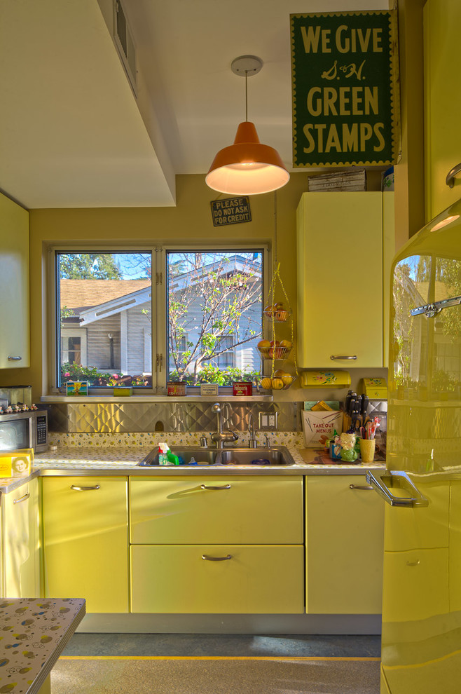 This is an example of an eclectic kitchen in Los Angeles with yellow cabinets, metallic splashback and metal splashback.